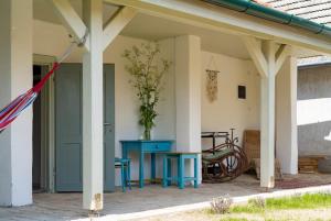 un porche con una mesa azul y una planta en Zamatos Turbolya Kisház és Wellness, en Pannonhalma