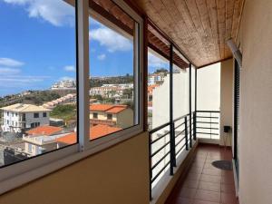 a balcony with windows and a view of a city at Por do Sol in Caniço