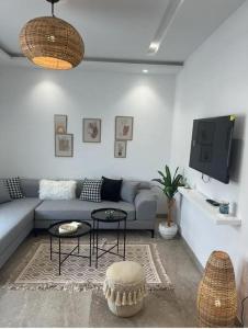 uma sala de estar com um sofá e uma televisão em Appartement avec piscine et 10 min plage em Hammamet Nord