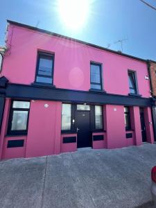 un bâtiment rose avec une porte noire dans l'établissement Codladh Sámh, à Templemore