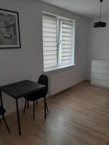 biały pokój ze stołem i oknem w obiekcie Apartamenty niedaleko plaży w Brodnicy