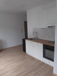 kuchnia z białymi szafkami i drewnianą podłogą w obiekcie Apartamenty niedaleko plaży w Brodnicy