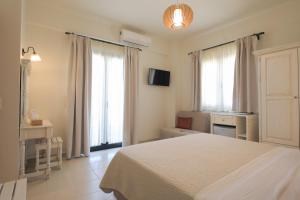 a bedroom with a white bed and two windows at Philharmonie Hotel in Kalamaki Heraklion