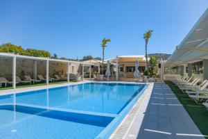 a swimming pool with chairs and a house at Philharmonie Hotel in Kalamaki