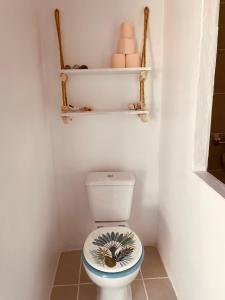 ein Bad mit einem WC, einem Regal und Handtüchern in der Unterkunft Tikehau cosy lodge in Tikehau