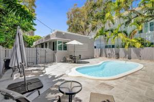 una piscina en un patio con sillas y sombrilla en Retro Oasis by Las Olas en Fort Lauderdale