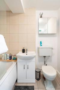 Baño blanco con aseo y lavamanos en Perfect for Large Family & Friends, Free Parking, Games en Reading