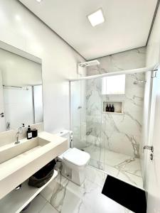 a bathroom with a toilet and a glass shower at Apto Loft Novo - Porto Belo - 5 min a pé da praia in Porto Belo