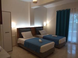 2 camas en una habitación con cortinas azules en Tzafi's Apartments 2, en Mesongi