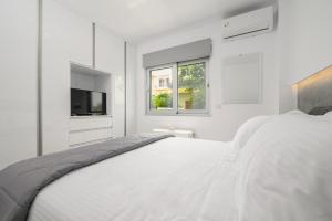 een witte slaapkamer met een bed en een televisie bij Aetherius Executive Suite 5 Min to BEACH in Kos-stad