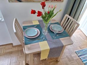 einen Esstisch mit einer Vase roter Tulpen in der Unterkunft Apartment Drazica in Opatija