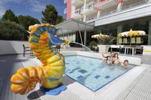 a group of children in a swimming pool with a seahorse statue at Hotel Eden in Bibione