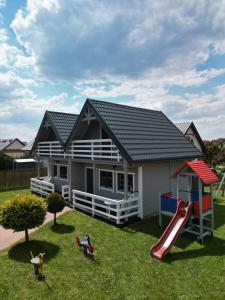 une maison avec un toboggan et une aire de jeux dans l'établissement Domki i apartamenty Mila, à Sarbinowo