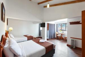 una camera d'albergo con due letti e una scrivania di Hotel Amerinka a Cuzco