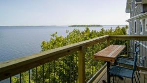 a table and chairs on a balcony overlooking the water at Loza house coastal design unit with lake & mountain views in Plattsburgh