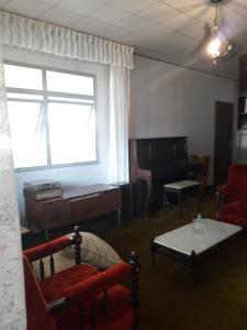 ein Wohnzimmer mit Sofa und Klavier in der Unterkunft Quartos em Casa próximo ao Parque Bacacheri in Curitiba