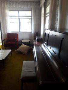 a room with a living room with a couch and a chair at Quartos em Casa próximo ao Parque Bacacheri in Curitiba