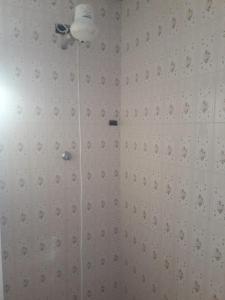 uma casa de banho com um chuveiro e uma parede de azulejos brancos. em Quartos em Casa próximo ao Parque Bacacheri em Curitiba