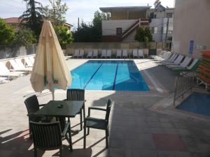 a pool with a table and an umbrella and chairs at Nazar Hotel in Didim