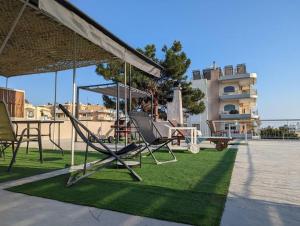 eine Terrasse mit Stühlen, einem Tisch und einer Schaukel in der Unterkunft Sunny Terrace in Glyfada in Athen