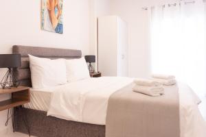 um quarto com uma cama com lençóis brancos e toalhas em SKG Dream Residence em Tessalônica