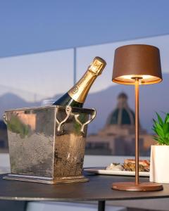 una botella de champán en un cubo de metal sobre una mesa en Mazzini Accommodation, en Favignana