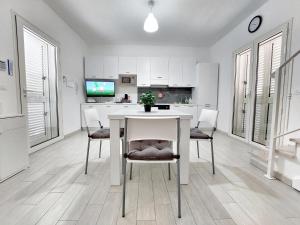 biała kuchnia z białym stołem i krzesłami w obiekcie Villa Ivan Spiaggiabianca Deluxe - A 20 metri dal mare w mieście San Pietro in Bevagna