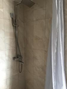 La salle de bains est pourvue d'une douche avec rideau de douche. dans l'établissement Апартаменты в Старом городе, à Kamianets-Podilsky