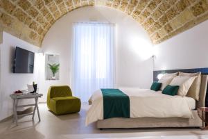 a bedroom with a large bed and a green chair at Casa Minerva - Suite e Relax in Gioia del Colle