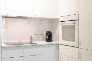 Una cocina blanca con gabinetes blancos y un electrodoméstico negro. en Vilda Point, en Poznan