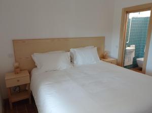 a bedroom with a large white bed and a bathroom at Casa do Livramento in Luz de Tavira