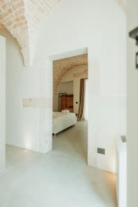 Una habitación blanca con una cama a lo lejos. en Palazzo Le Marangi, en Martina Franca