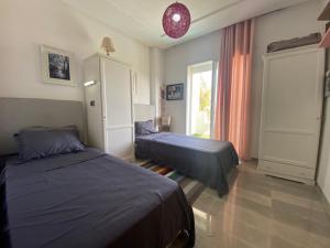 1 Schlafzimmer mit 2 Betten und einem Fenster in der Unterkunft Apparemment de luxe in Hammamet