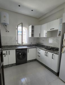 cocina con armarios blancos y lavadora en Maison Sidi bouzid en Sidi Bouzid