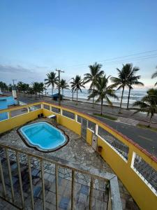Hostel Encanto de Mongaguá في مونغاغوا: حمام سباحة على جانب مبنى مع الشاطئ