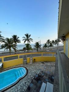 uma piscina ao lado de uma praia com palmeiras em Hostel Encanto de Mongaguá em Mongaguá