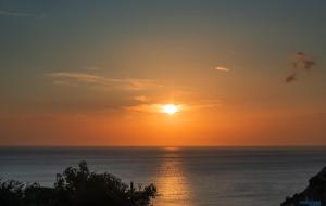un tramonto sull'oceano con il sole nel cielo di Blue Bay Villas , Ground Floor a Archangelos