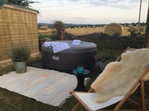 a hot tub in a yard with a table and a chair at Dolly’s shepherds hut in Trowbridge