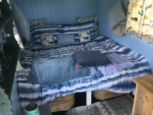 a bed with a blue and white blanket and pillows at Dolly’s shepherds hut in Trowbridge
