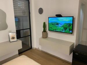 a living room with a flat screen tv on a wall at חדר סטודיו בסגנון נורדי in Sede Naẖum