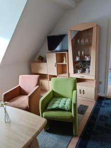 a living room with a green chair and a cabinet at Nette Kuschelige Wohnung in Bochum