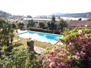 een zwembad in een tuin met roze bloemen bij VNC13V4, encantadora casa e piscina, vista rio Min in Gondarém