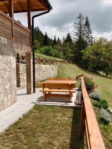 a wooden picnic table in a garden with a stone wall at Zaovinska Panorama I in Bajina Bašta