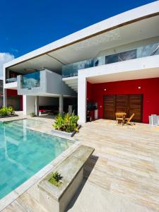 a house with a swimming pool and a red wall at Vila Kite Lagoon in Parajuru +42 photos