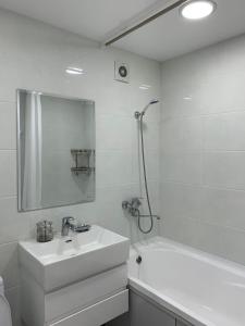 ein weißes Bad mit einem Waschbecken und einer Dusche in der Unterkunft Apartment Guli in Taschkent