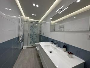 La salle de bains blanche est pourvue d'un lavabo et d'une douche. dans l'établissement Luxury B&B Sun Art Naples, à Naples