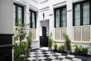 a white house with potted plants on a checkered floor at San Buenaventura Apartment 13 in Seville