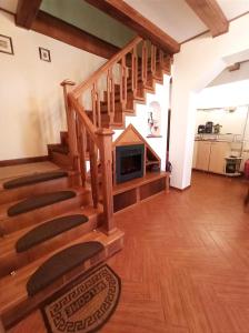 a living room with a wooden staircase with a fireplace at Pensiunea Roșu Litoral in Douăzeci şi Trei August