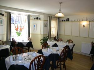 un comedor con 2 mesas y sillas con manteles blancos en Cromwell House, en Eastbourne