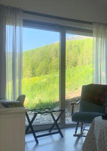 a room with a large window with a chair and a table at B&B Tantané in Torgnon